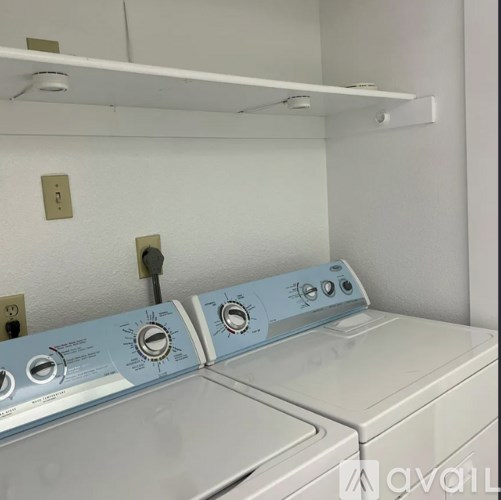 A washing machine with a blue control panel is in a laundry room.