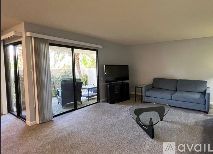 A living room with a grey couch, a black television, and a glass door leading to a patio.