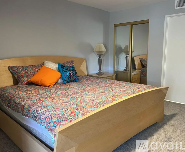 A bed with a wooden headboard and a colorful bedspread with two pillows on it.