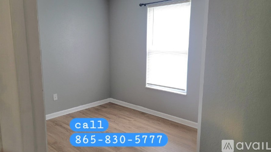 A room with a window and a phone number on the wall.