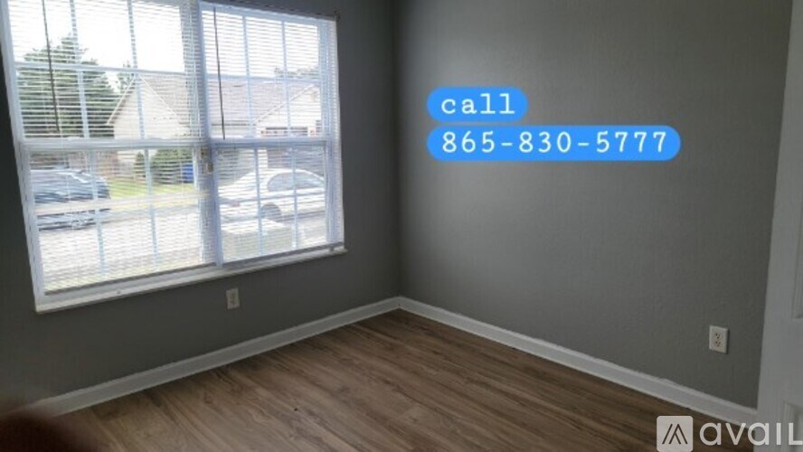 A room with a large window and a phone number displayed on the wall.