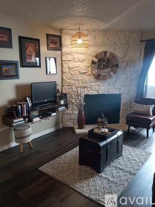 A living room with a stone fireplace and a flat screen TV.