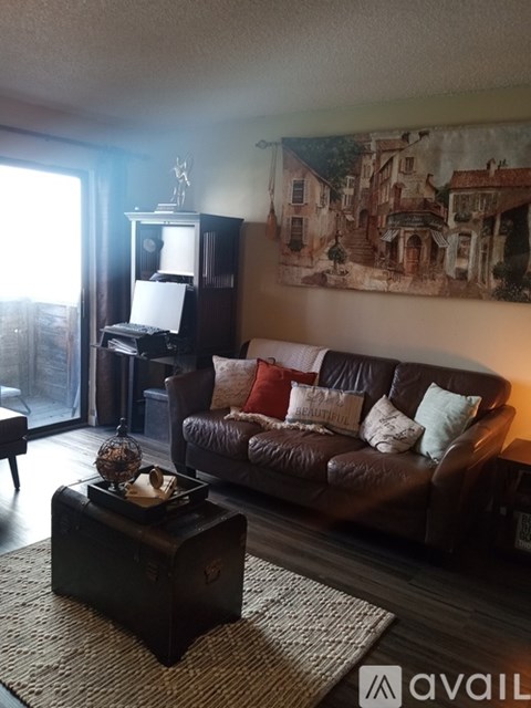 A living room with a brown couch and a painting on the wall.