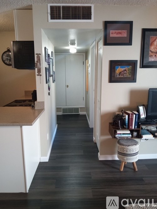 A hallway with a white door and a wall with pictures on it.