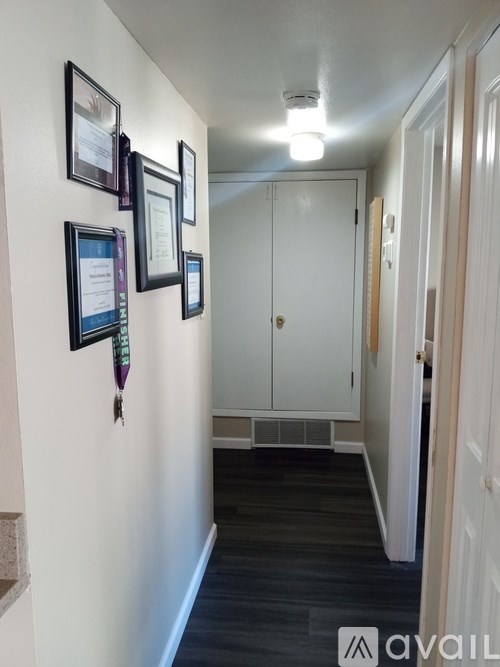 A hallway with a white door and pictures on the wall.