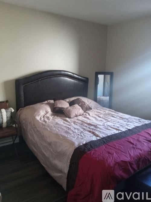 A bed with a black headboard and a purple blanket.