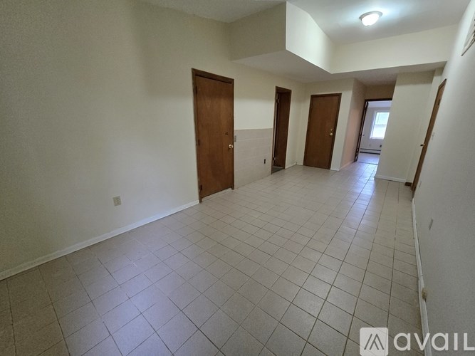A spacious room with tiled flooring and three doors.