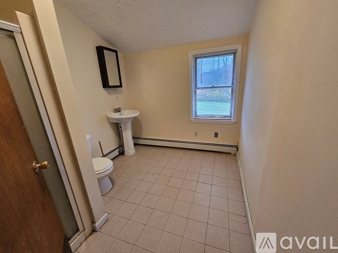 A small bathroom with a toilet, sink, and window.