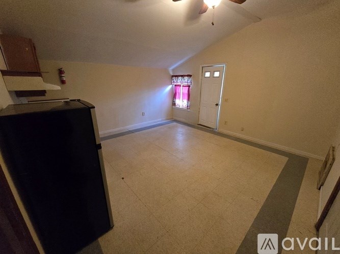 A room with a black cabinet and a window with red curtains.