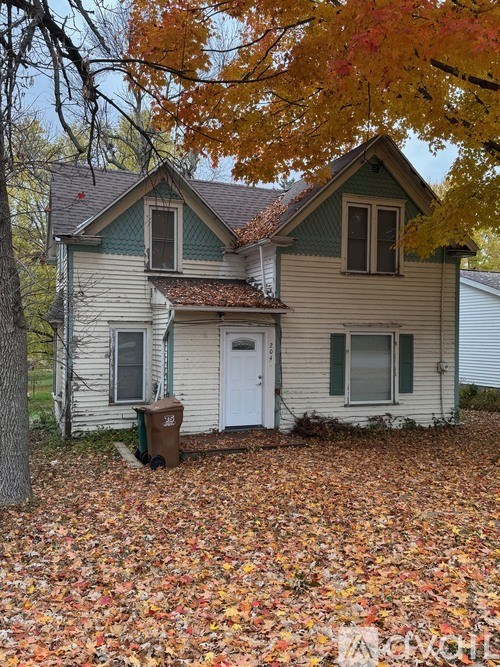 A house with a white door and a brown trash can in front of it.