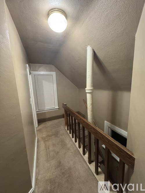 A narrow hallway with a light on the ceiling and a door at the end.