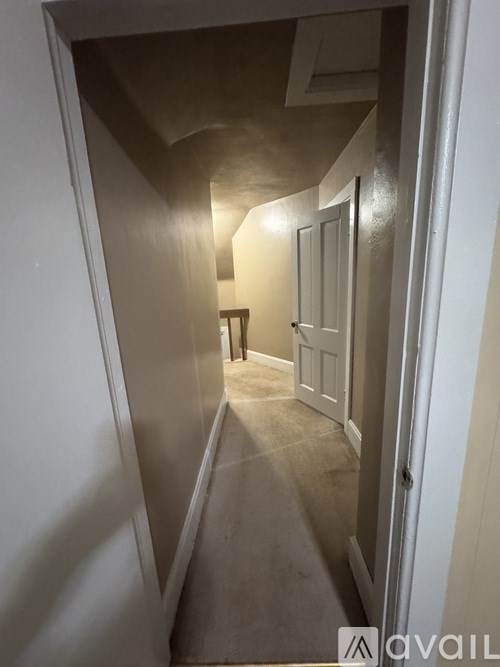 A hallway with a carpeted floor and white walls.