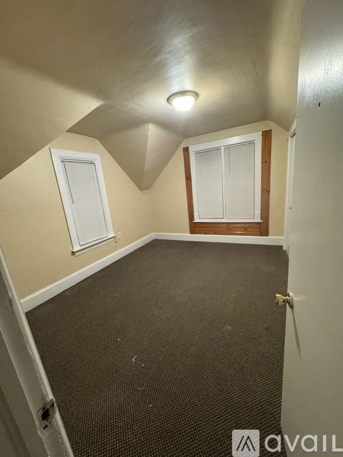 A room with a carpeted floor and a window with blinds.