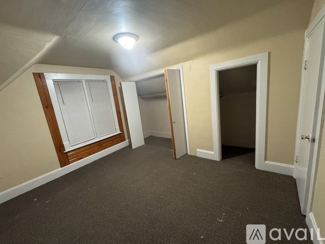 A room with a carpeted floor and a window with blinds.