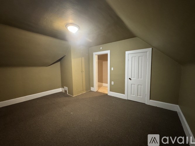 A room with a carpeted floor and two doors, one of which is open.