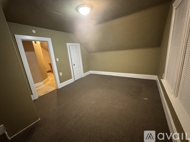 A room with a carpeted floor and a door leading to another room.