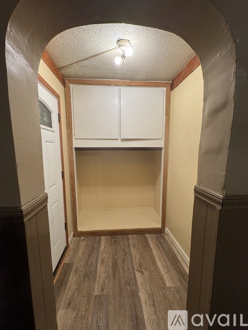 A small, empty room with a wooden floor and a white cabinet.