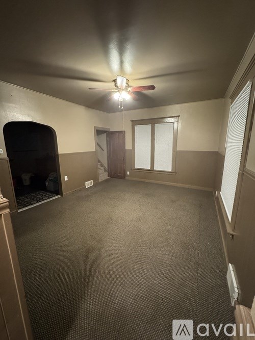 A room with a carpeted floor and a ceiling fan.