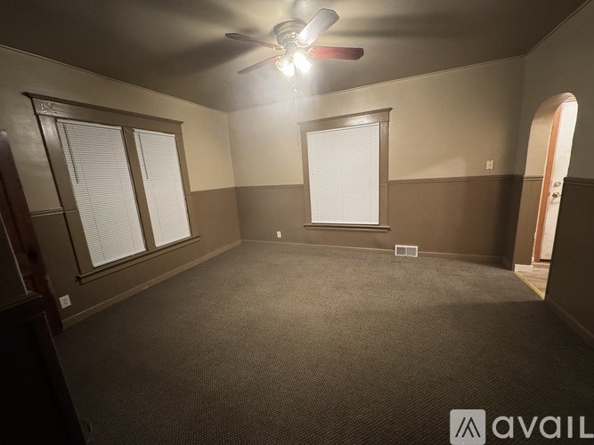A room with a ceiling fan and carpeted floor.