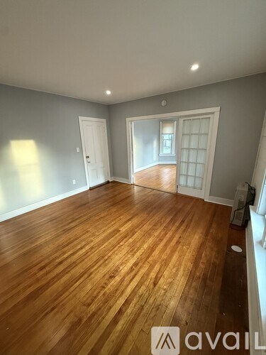 A room with wooden flooring and white walls.