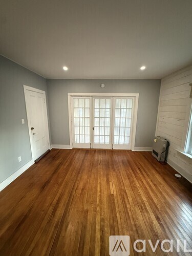 A room with wooden flooring and a window with blinds.