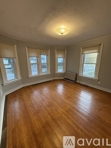 A room with wooden floors and three windows.