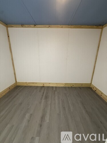 A room with wooden flooring and white walls.