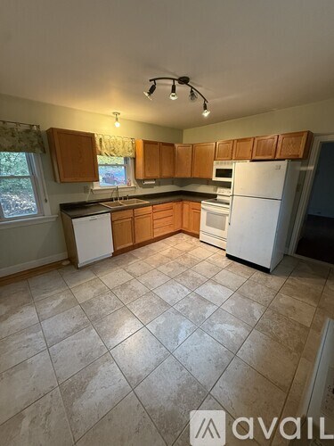 A kitchen with tile flooring and wooden cabinets.