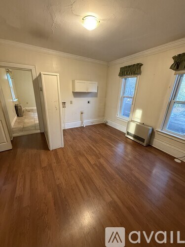 A room with wooden floors and a window with a green curtain.