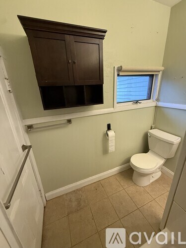 A small bathroom with a toilet and a cabinet above it.