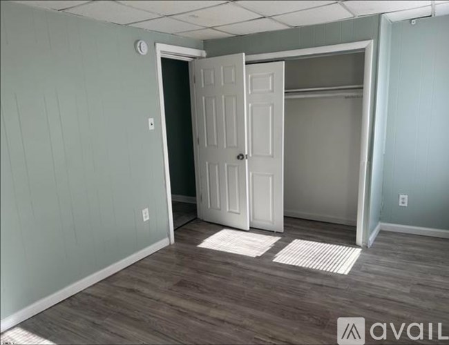 A room with a white door and a wooden floor.