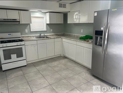 A kitchen with white cabinets and a stainless steel refrigerator.