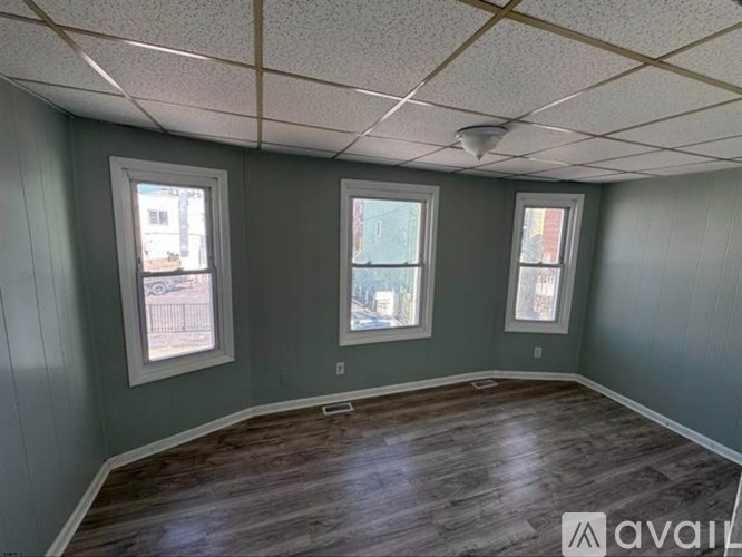 A room with wooden floors and three windows.