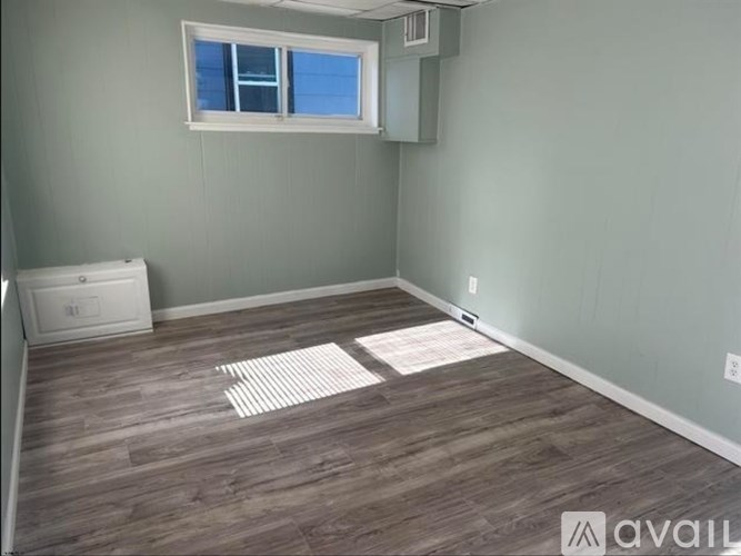 A room with a window and wooden flooring.