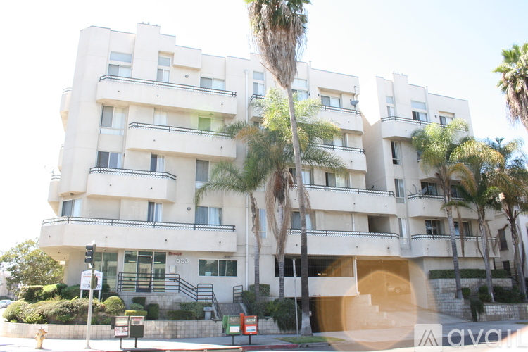 A white apartment building with balconies and palm trees in front.