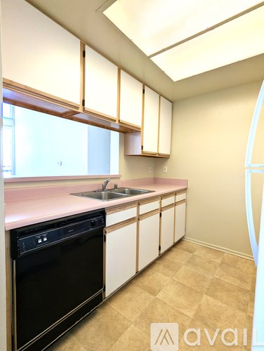 A kitchen with a black dishwasher and a pink countertop.
