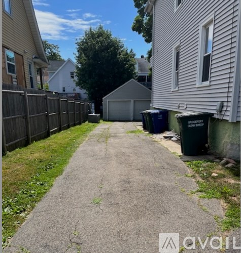 A residential alley with a wooden fence on the left and a white house on the right.