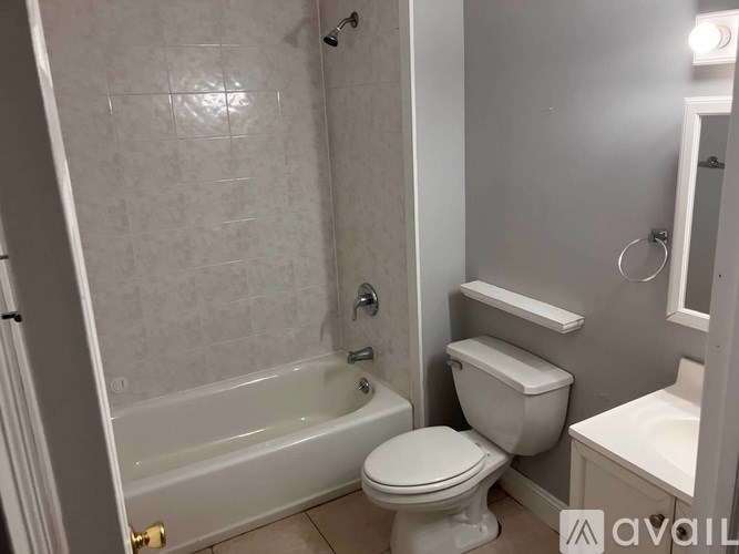 A white toilet is in a bathroom with a walk-in shower.