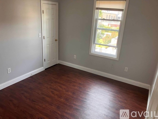 A room with a wooden floor and a window with blinds.