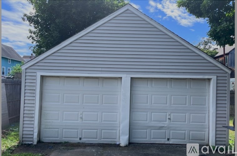 A two-car garage with white doors is situated in a yard.