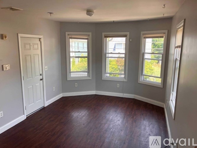A room with wooden floors and three windows.