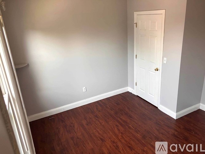 A room with a white door and wooden flooring.