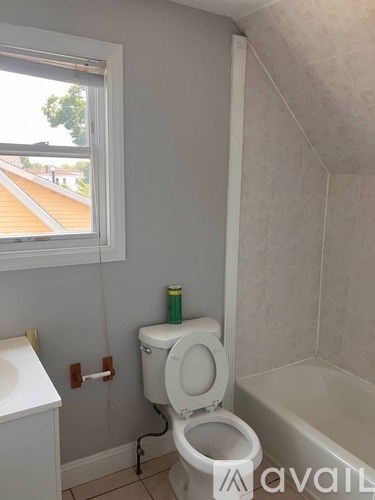 A white toilet in a bathroom with a window.