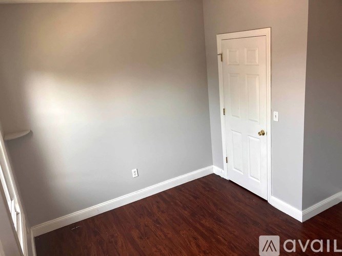 A room with a white door and wooden floor.
