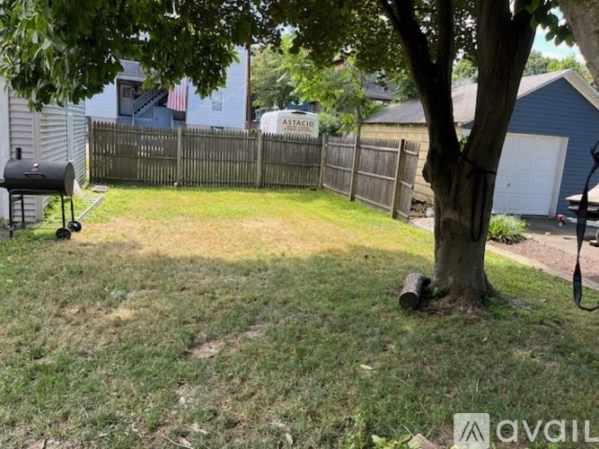 A backyard with a tree, a fence, and a mailbox.