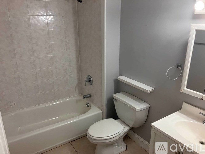 A white toilet sits next to a bathtub in a bathroom.