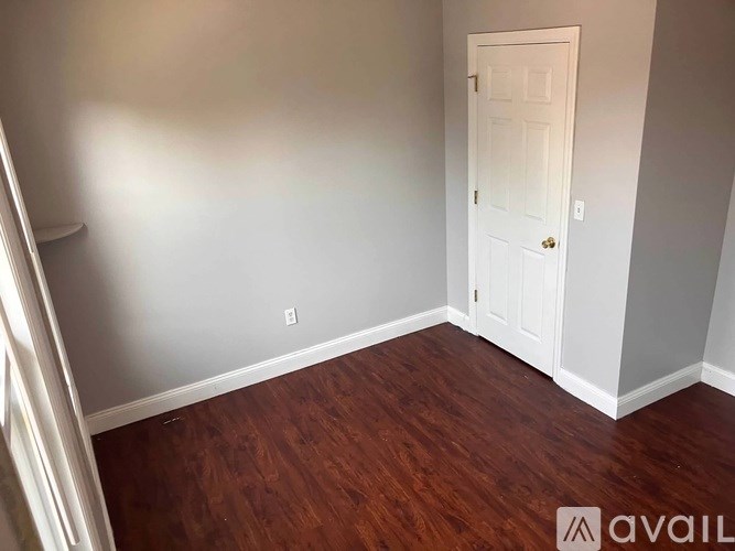 A room with a white door and wooden flooring.