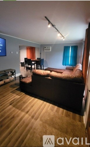 A living room with a brown sofa and a wooden floor.