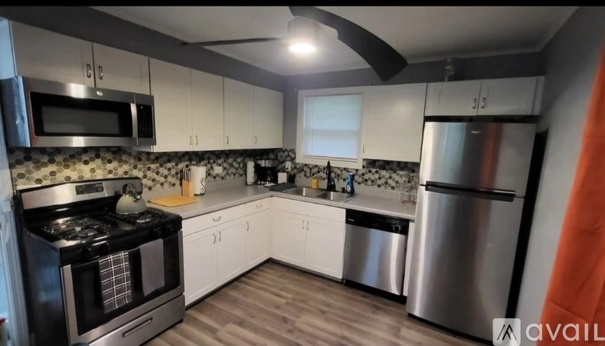 A modern kitchen with stainless steel appliances and wooden flooring.