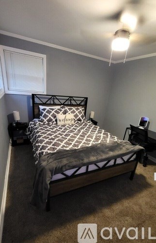 A bed with a black metal frame and a white and black patterned comforter is in a room with a carpeted floor.